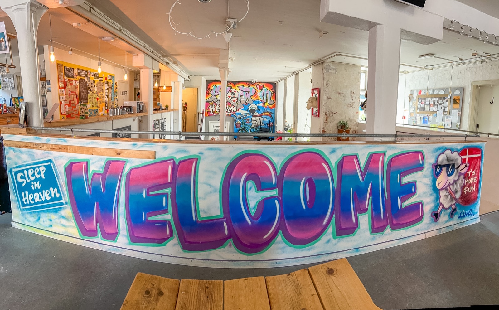 Fisheye view of the completed Welcome mural wrapping the hostel bar in Denmark